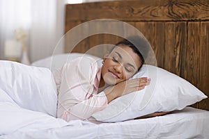 Healthy sleeping concept. Peaceful african american woman sleeping in her bed at home, resting in white cozy bedroom