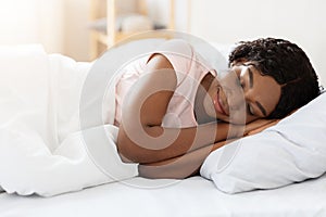 Smiling pretty black woman sleeping in her bed at home photo