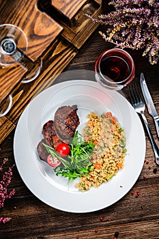 grilled meat and couscous on wood table