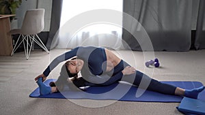 Healthy slim woman on fitness mat doing warm up exercise. Fit woman sitting stretching. Positive well-fit lady in