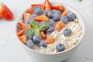 Healthy smoothie bowl with granola, fresh strawberries, blueberries, bananas, yogurt and mint.