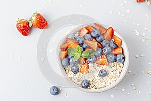 Healthy smoothie bowl with granola, fresh strawberries, blueberries, bananas, yogurt and mint.