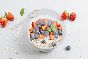 Healthy smoothie bowl with granola, fresh strawberries, blueberries, bananas, yogurt and mint.