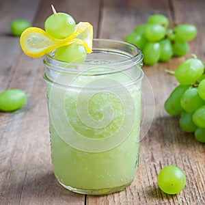 Healthy smoothie with green grape, lemon and honey in glass jar, square