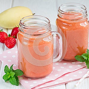 Healthy smoothie with strawberry, mango and banana in glass jars, square format