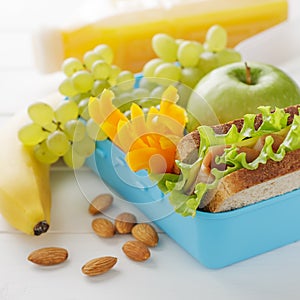 Healthy snack in blue plastic lunch box on white wooden table.