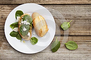 Healthy snack. Bun or bread with pesto pasta and basil leaves. Rustic wooden table, top view.