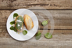 Healthy snack. Bun or bread with pesto pasta and basil leaves. Rustic wooden table, top view.