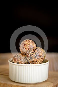 Healthy snack. Energy ball with date plam, black and white sesame, chia and rasin in ceramic bowl on wooden table. Vegan