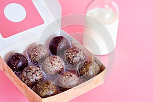 Healthy snack. Energy ball with date plam, black and white sesame, chia and rasin in paper box on pink background. Vegan