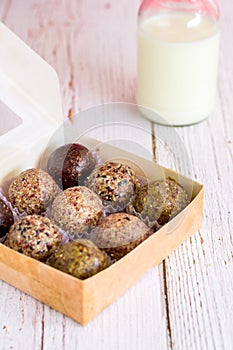 Healthy snack. Energy ball with date plam, black and white sesame, chia and rasin in paper box on wooden table. Vegan vegetarian