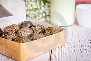 Healthy snack. Energy ball with date plam, black and white sesame, chia and rasin in paper box on wooden table. Vegan vegetarian