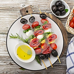 Healthy snack: mouth-watering kebabs on a picnic with tomatoes, mozzarella, salami, black olives, Basil, tortellini