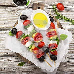 Healthy snack: mouth-watering kebabs on a picnic with tomatoes, mozzarella, salami, black olives, Basil, tortellini