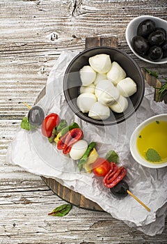 Healthy snack: mouth-watering kebabs on a picnic with tomatoes, mozzarella, salami, black olives, Basil, tortellini