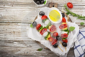 Healthy snack: mouth-watering kebabs on a picnic with tomatoes, mozzarella, salami, black olives, Basil, tortellini