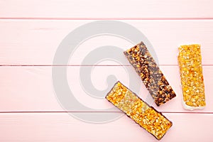 Healthy snack, muesli bars with raisins and dried berries on a pink background