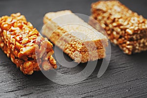 Healthy snacks. Fitness diet food. Grain bar with peanuts, sesame and seeds on a cutting board on a dark table, energy