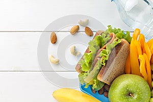 Healthy snacks in lunch box on white wooden background.