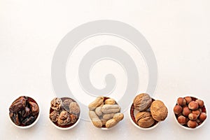 Healthy snacks nuts and dried fruits.  Top view of bowls on white table
