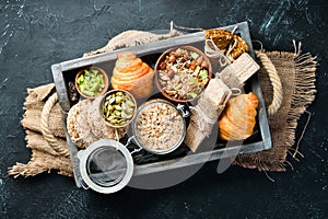 Healthy snacks in a wooden box. oatmeal bars, croissant, raisins, nuts. Top view. Free space