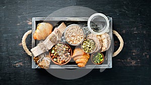 Healthy snacks in a wooden box. oatmeal bars, croissant, raisins, nuts. Top view.