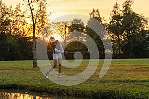 Healthy Sport. Asian Sporty woman golfer player chips and swing golf on the green sunset evening time, she presumably does exercis