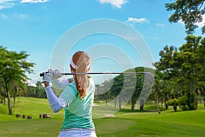 Healthy Sport. Asian Sporty woman golfer player doing golf swing tee off on the green evening time, she presumably does exercise.