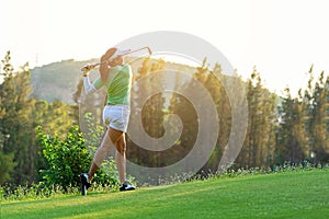Healthy Sport. Asian Sporty woman golfer player doing golf swing tee off on the green evening time, she presumably does exercise.