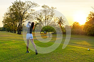 Healthy Sport. Asian Sporty woman golfer player doing golf swing tee off on the green evening time, she presumably does exercise.