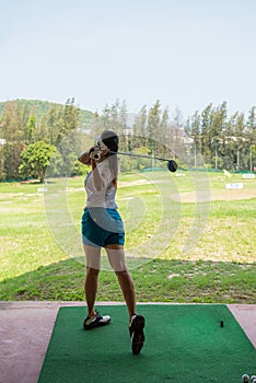 Healthy Sport.  Asian sporty woman swing golf ball practice at golf driving