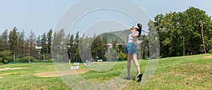 Healthy Sport.  Asian sporty woman swing golf ball practice at golf driving range on evening