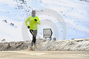 Healthy sport man running on asphalt road at snow mountains in trail runner hard workout in winter