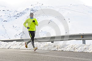 Healthy sport man running on asphalt road at snow mountains in trail runner hard workout in winter