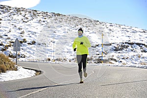 Healthy sport man running on road at snow mountains in trail runner hard workout in winter