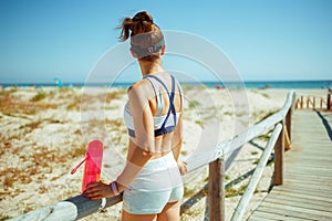 Healthy sports woman with bottle of water on seacoast