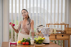 Healthy Sportsgirl holding dumbbell with food to maintain health on table in kitchen room at home