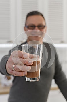 A healthy sporty senior man takes sport supplement protein from shaker before dinner. Active lifestyle for retirees