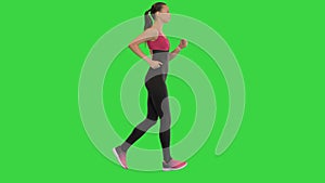 Healthy sporty young woman running and using smart watch device on a Green Screen, Chroma Key.