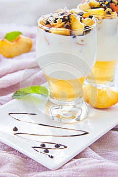 Healthy strawberry, peach and walnut parfait in a glass on a white background