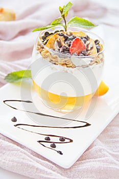 Healthy strawberry, peach and walnut parfait in a glass on a white background