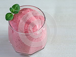 Healthy Strawberry or Raspberry Cream mousse in glass on a white wooden table with mint leaves. Delisious summer dessert