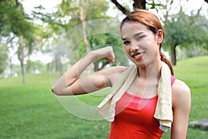 Healthy strong Asian woman in red sportswear showing her hands in natural park. Fitness and lifestyle concept.