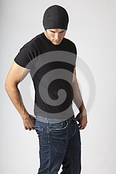 Healthy, strong, slim, slender young man wearing black t-shirt, jeans and knit hat. Young men`s modern casual clothing fashions st photo