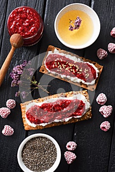 Healthy sugar free dessert and herbal tea. Raspberry chia jam on crispy bread and cream cheese with frozen berries on black