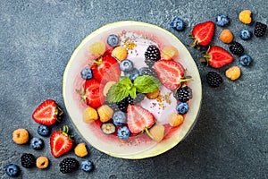 Healthy summer breakfast concept, fruit salad in carved watermelon. Watermelon bowl with yogurt, chia seeds, fresh berries