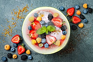 Healthy summer breakfast concept, fruit salad in carved watermelon. Watermelon bowl with yogurt, chia seeds, fresh berries