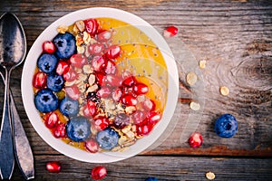 Healthy summer breakfast mango smoothie bowl with granola, blueberries, pomegranate and chia seeds