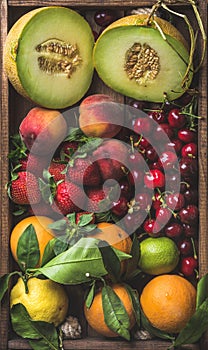 Healthy summer fruit variety. Melon, sweet cherries, peach, strawberry, orange and lemon on wooden tray background