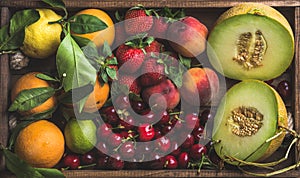 Healthy summer fruit variety. Melon, sweet cherries, peach, strawberry, orange and lemon on wooden tray background